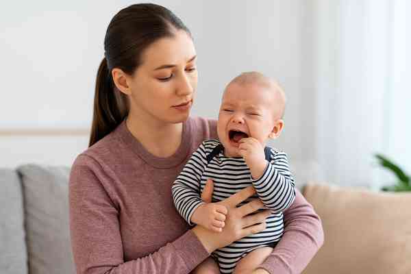 Mother comforting her 10-week-old teething baby during feeding and sleep routine